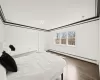 Bedroom with hardwood / wood-style flooring, crown molding, and baseboard heating