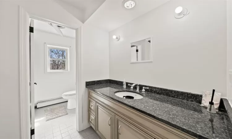 Bathroom with vanity, toilet, and a baseboard heating unit