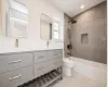 Full bathroom with vanity, tiled shower / bath combo, and toilet