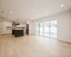 Kitchen with a center island, hanging light fixtures, wall chimney exhaust hood, stainless steel fridge, and white cabinetry