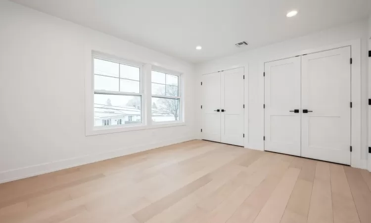 Bedroom with light hardwood floors and multiple closets