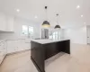 Kitchen featuring white cabinetry, sink, quartz backsplash, stainless steel fridge, and a kitchen island