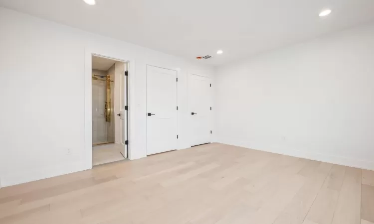 Unfurnished bedroom with light hardwood floors and connected bathroom