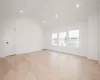 Primary Bedroom w light hardwood floors and vaulted ceiling