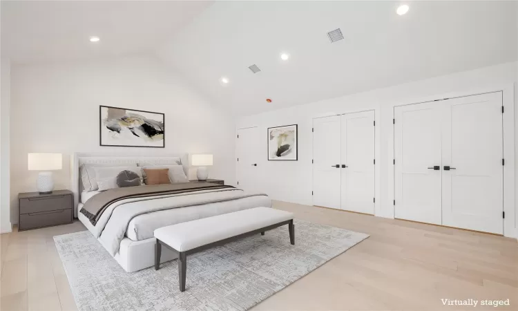 Virtually Staged Primary Bedroom featuring light hardwood floors, high vaulted ceiling, and multiple closets