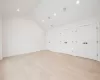 Primary bedroom featuring multiple closets, light hardwood flooring, and lofted ceiling