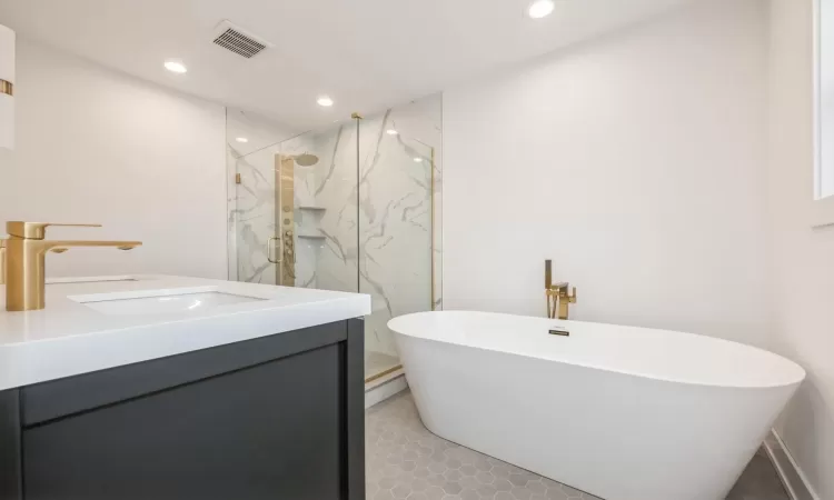 Primary bathroom featuring tile patterned flooring, vanity, and separate shower and tub