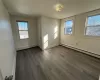 Unfurnished bedroom with baseboard heating and dark hardwood / wood-style floors