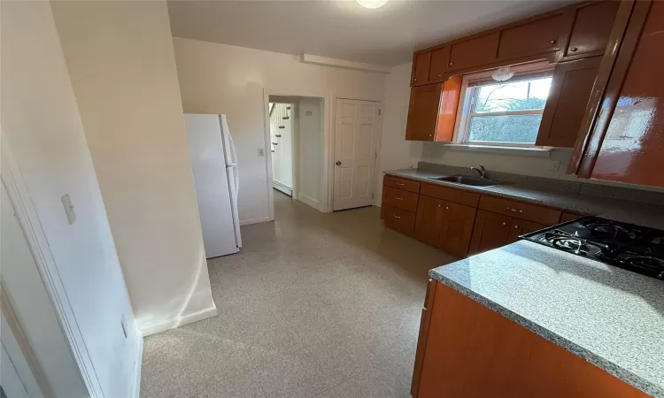 Kitchen featuring white refrigerator, gas stovetop, sink, and a baseboard radiator