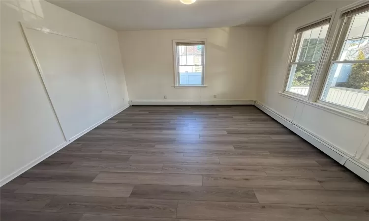 Empty room featuring plenty of natural light, dark hardwood / wood-style flooring, and baseboard heating