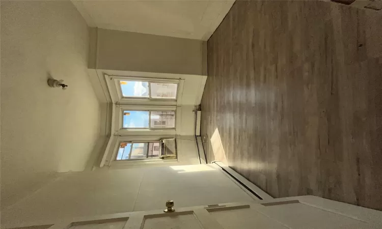 Empty room with a textured ceiling, plenty of natural light, dark hardwood / wood-style floors, and a baseboard heating unit