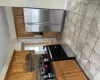 Kitchen with ventilation hood, refrigerator, dark stone counters, decorative backsplash, and range