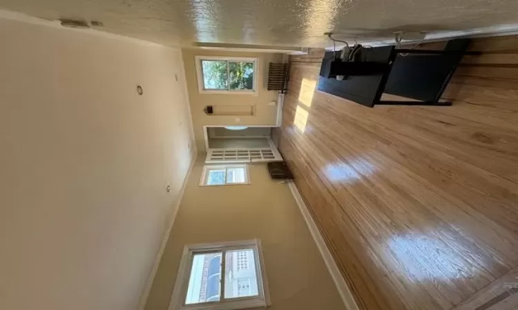 Living room with radiator heating unit, light hardwood / wood-style floors, and crown molding