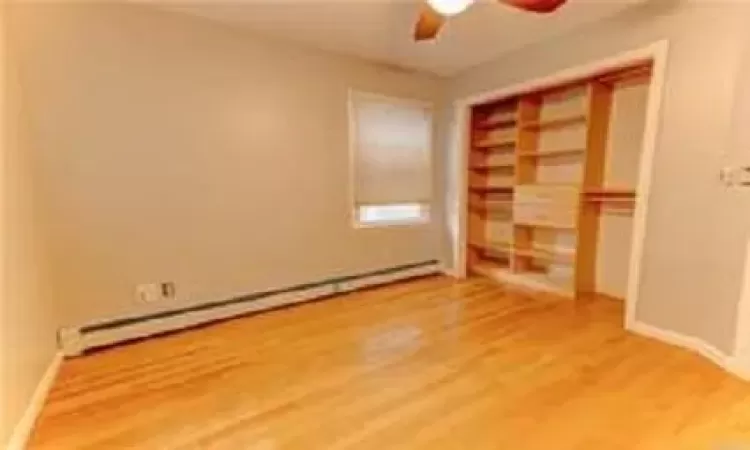 Spare room with hardwood / wood-style floors, a baseboard radiator, and ceiling fan