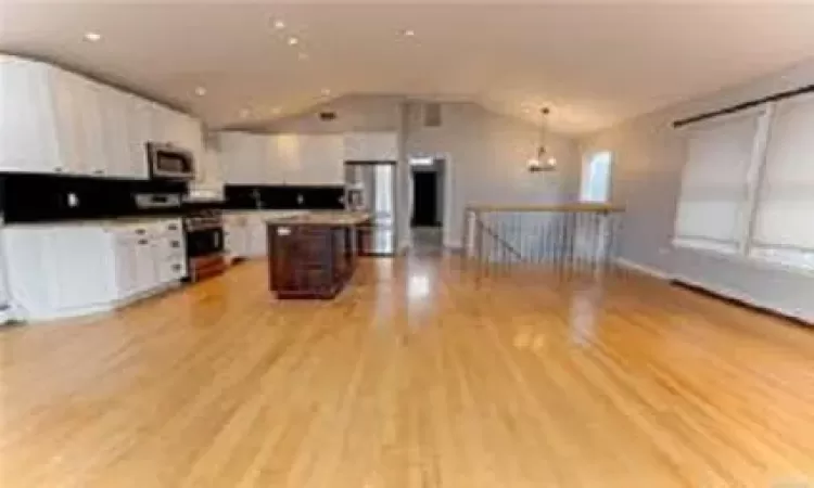 Kitchen featuring a center island, hanging light fixtures, stove, light hardwood / wood-style floors, and white cabinets