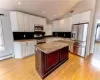 Kitchen featuring a kitchen island, light stone countertops, white cabinetry, and stainless steel appliances