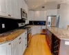 Kitchen featuring white cabinets, light hardwood / wood-style floors, appliances with stainless steel finishes, a kitchen island, and light stone counters