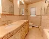 Bathroom with toilet, vanity, tile patterned floors, and tile walls