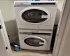 Laundry area with stacked washer / drying machine and light wood-type flooring