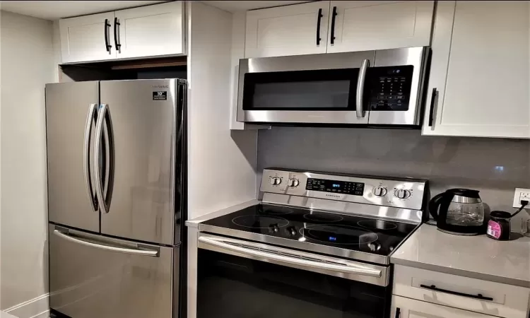 Kitchen featuring stainless steel appliances and white cabinetry