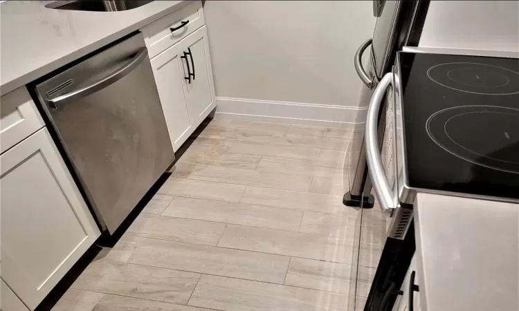 Kitchen with white cabinetry, dishwasher, and range