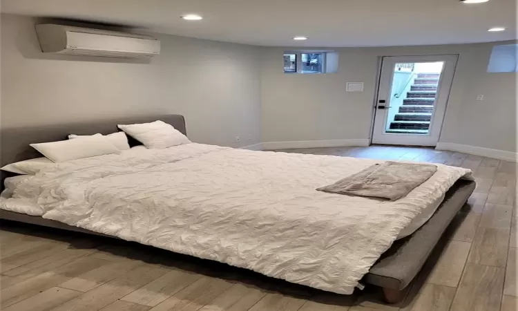 Bedroom featuring access to outside, light hardwood / wood-style floors, and a wall mounted air conditioner