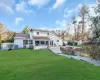 Rear view of property featuring a sunroom, a patio, cooling unit, and a lawn