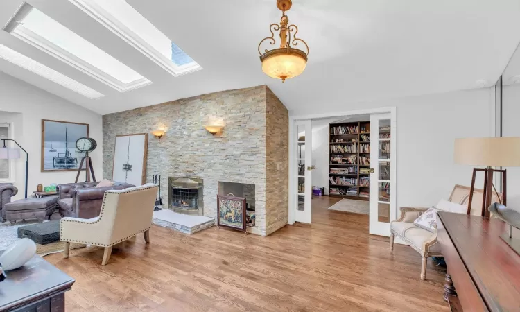 Living room featuring a fireplace, lofted ceiling with skylight, and light hardwood / wood-style flooring