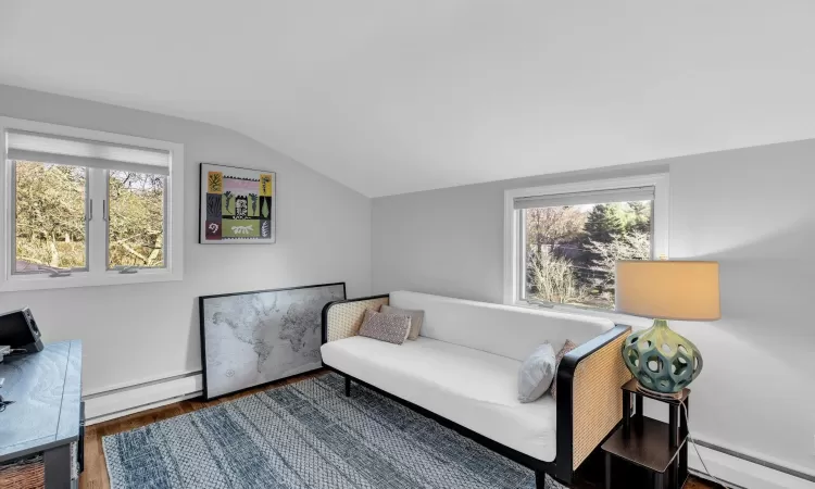 Living area featuring baseboard heating, a wealth of natural light, and lofted ceiling