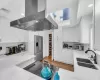 Kitchen with appliances with stainless steel finishes, light stone counters, sink, wall chimney range hood, and white cabinets