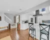 Kitchen with island exhaust hood, appliances with stainless steel finishes, decorative backsplash, light hardwood / wood-style flooring, and white cabinets