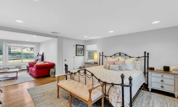 Bedroom with baseboard heating and hardwood / wood-style floors