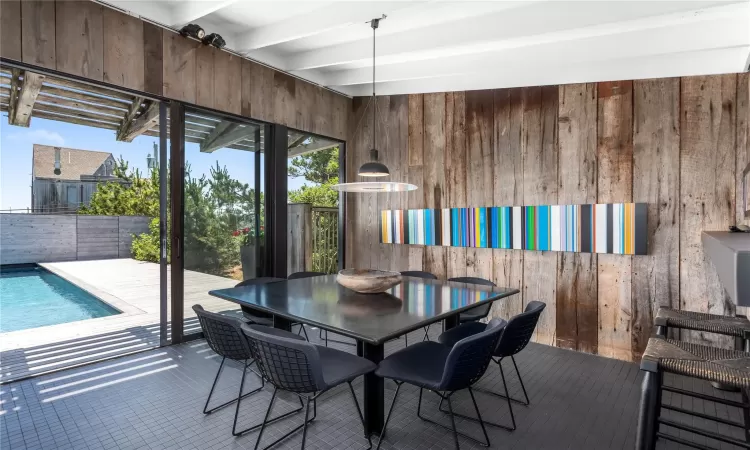 Dining area with tile patterned flooring, beamed ceiling, and wood walls