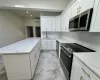 Kitchen featuring white cabinets, light stone counters, sink, and stainless steel appliances