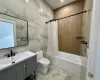 Full bathroom with shower / bath combination with curtain, toilet, tile walls, and vanity