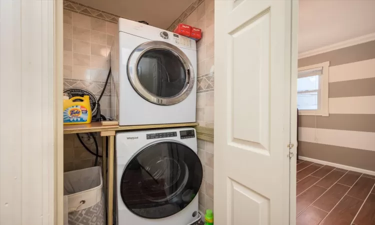 Laundry area with ornamental molding and stacked washer / dryer