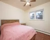 Bedroom with ceiling fan and a baseboard heating unit