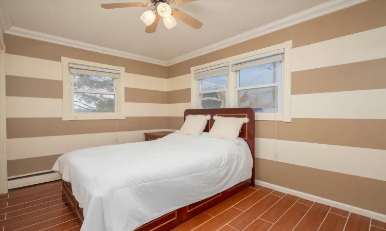 Bedroom with ceiling fan, ornamental molding, and a baseboard heating unit