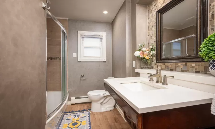 Bathroom with vanity, hardwood / wood-style flooring, toilet, and baseboard heating