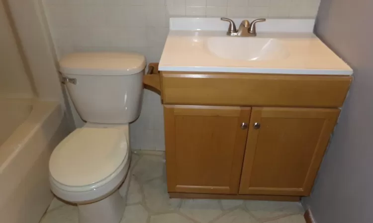 Bathroom featuring a bathing tub, vanity, and toilet