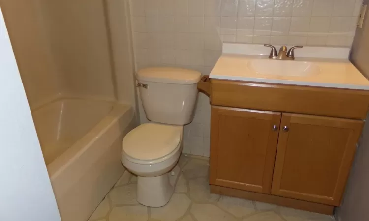 Bathroom featuring vanity, tasteful backsplash, toilet, and tile walls