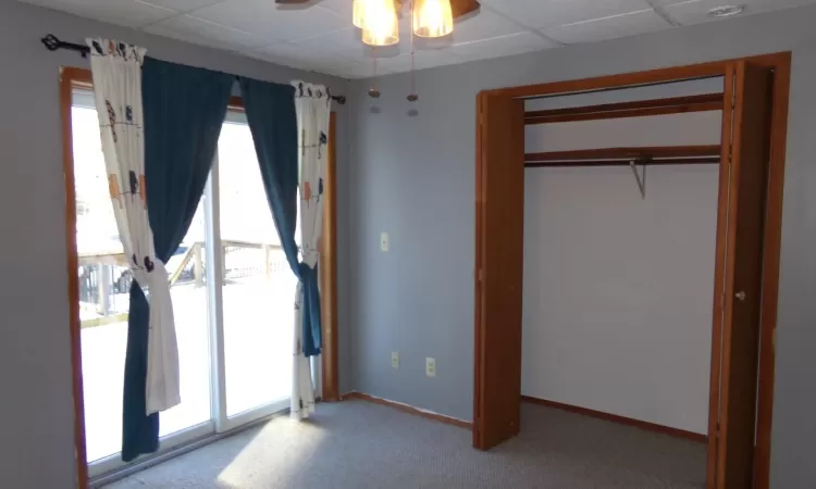 Unfurnished bedroom featuring light carpet, a closet, and ceiling fan