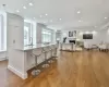 Kitchen with white cabinetry, light stone counters, a large island with sink, a kitchen bar, and light wood-type flooring