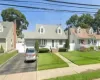 Cape cod house featuring a garage and a front lawn