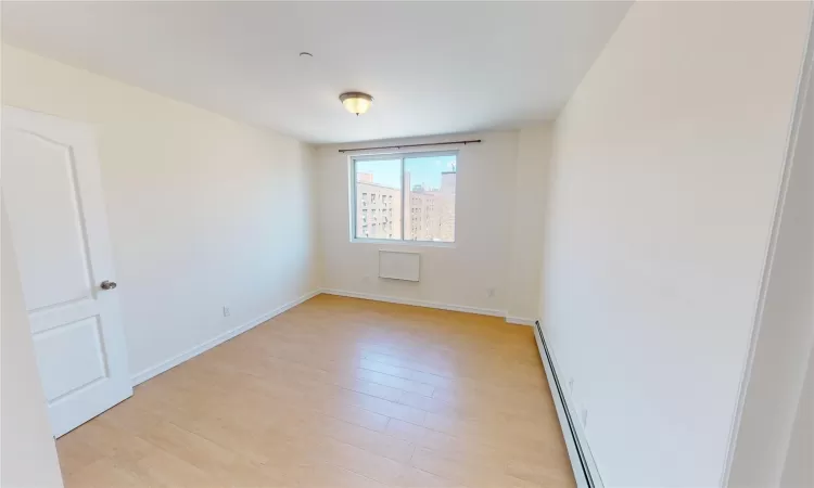 Unfurnished room featuring light hardwood / wood-style flooring and a baseboard heating unit