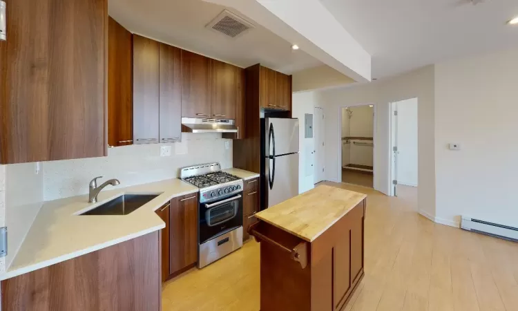 Kitchen featuring appliances with stainless steel finishes, backsplash, sink, light hardwood / wood-style floors, and butcher block counters