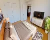 Bedroom featuring stainless steel fridge, light wood-type flooring, and a closet