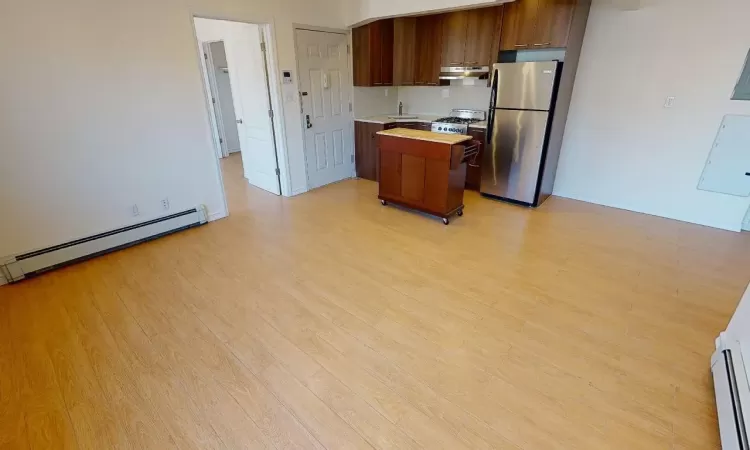 Kitchen featuring a baseboard heating unit, stainless steel fridge, light hardwood / wood-style floors, decorative backsplash, and a kitchen island