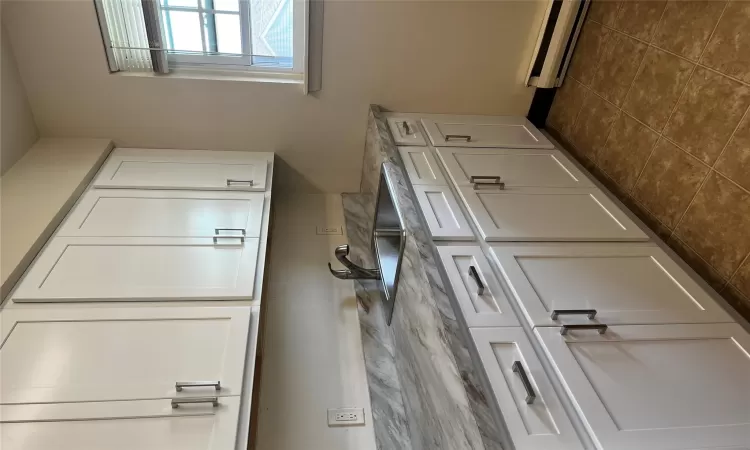 Kitchen with white cabinets, light stone countertops, sink, and a baseboard heating unit