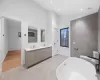 Bathroom featuring vanity, toilet, a tub, and high vaulted ceiling